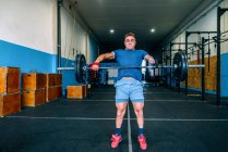 Мощный спортсмен без ручного подъема тяжелого веса во время функциональной тренировки возле спортивного инвентаря в спортзале — стоковое фото