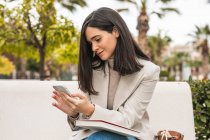 Concentrated female entrepreneur using smartphone in street while checking messages in email — Stock Photo