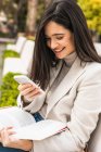 Smile female entrepreneur using smartphone in street while checking messages in email — Stock Photo