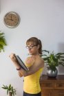 Mujer adulta en ropa casual viendo vídeo en la tableta moderna en la sala de estar de luz - foto de stock