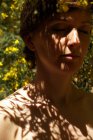 Ruhige erwachsene nackte Weibchen mit geschlossenen Augen ruhen im Garten in der Nähe blühenden Baum mit gelben Blüten an sonnigen Tag — Stockfoto