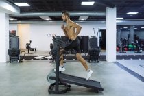 Seitenansicht Ganzkörper von starken ausdauernden Mann Training auf Sportgeräten in geräumigen Fitnessraum — Stockfoto