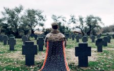 Visão traseira corpo cheio de soldado de uniforme sentado na cadeira com bandeira americana enquanto luto morte de guerreiros no cemitério — Fotografia de Stock