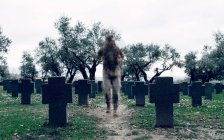 Anonymer Soldat in Tarnkleidung mit Kriegerrucksack läuft auf geräumigem Soldatenfriedhof — Stockfoto