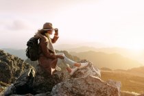 Vista laterale di escursionista irriconoscibile seduto sulla pietra e osservando paesaggi incredibili della valle degli altopiani nella giornata di sole — Foto stock