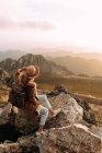 Seitenansicht eines nicht wiedererkennbaren Wanderers, der auf Stein sitzt und an sonnigen Tagen die atemberaubende Landschaft des Hochlandtals beobachtet — Stockfoto