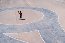Зверху баскетболіст бігає з м'ячем на бетонному майданчику під час тренувальних навичок у сонячний день — стокове фото