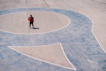 D'en haut du joueur de basket-ball se reposant avec la balle sur le terrain en béton pendant les compétences d'entraînement dans la journée ensoleillée — Photo de stock