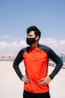 Männlicher Athlet in Maske steht mit den Händen auf der Taille im sonnigen Park vor dem Outdoor-Training — Stockfoto