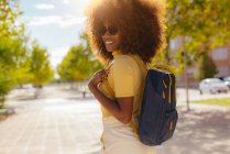 Black woman with curly hair walking down the street and laughing happily — Photo de stock