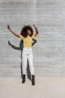 Black woman with afro hair listening to music on mobile in front of a gray wall — Stock Photo