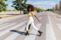 Schwarze Frau mit Afro-Haaren überquert mit Rucksack in der Hand die Straße — Stockfoto