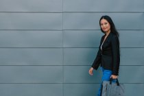 Сама впевнена в собі азіатська жінка-підприємець йде по вулиці біля міського будинку і озирається — стокове фото