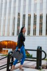 Вид збоку добре одягнена етнічна жінка-підприємець, що йде нагору на вулиці мегаполісу і дивиться в сторону — стокове фото