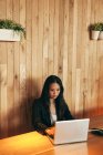Empreendedora asiática ocupada sentada à mesa no café enquanto come sushi e trabalha em projeto remoto via netbook — Fotografia de Stock