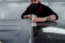 Mécanicien masculin occupé dans le ruban adhésif masque sur la voiture avant de peindre en atelier — Photo de stock