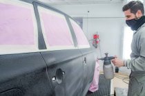 Вид збоку працівника чоловічої статі в масці та уніфікованому живописі автомобіля при використанні фарби — стокове фото