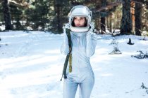 Зосереджена молода астронавтка в космосі і шоломі, дивлячись і стоячи в засніженому лісі — стокове фото