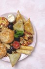 Высокий угол ассортимента вкусной арабской кухни с сальсой и свежими листьями мяты возле миндаля во время праздников Рамадан — стоковое фото