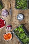 Top view composition of various fresh vegetables including radish cherry tomatoes onion and mixed salad leaves on wooden table — Stock Photo