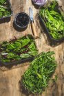 Vista dall'alto disposizione di foglie fresche mix insalate in ciotole da asporto posto sul tavolo vicino olive nere e cipolle tagliate — Foto stock