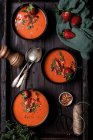 Komposition von oben mit köstlicher hausgemachter Tomaten- und Erdbeer-Gazpacho-Suppe, serviert in Schalen auf rustikalem Holztisch — Stockfoto