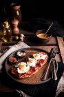Appetizing bread toast with prosciutto and fried quail eggs served for breakfast on rustic wooden table — Stock Photo
