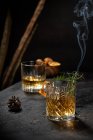 Verre en cristal de vieille boisson au whisky garni de romarin frais et d'écorce d'orange sur une table noire — Photo de stock