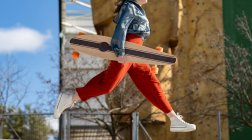 From below side view of cropped unrecognizable happy young female in stylish apparel jumping on the street — Fotografia de Stock