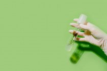 Урожай неузнаваемый ученый с растением в пластиковой трубке на зеленом фоне в студии — стоковое фото