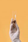 Обрізати невпізнаваного вченого з рослиною в пластиковій трубці на жовтому тлі в студії — стокове фото