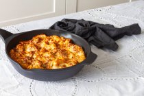 Appetizing gratin macaroni with meatballs and tomato sauce with mozzarella cheese prepared and served in skillet on table — Stock Photo