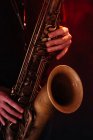 Crop безликий професійний музикант грає на саксофоні з пальцями на ключах під час живого концерту в неонових вогнях — стокове фото