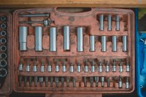 From above of old box with screwdriver and various nozzles and wrenches for auto maintenance and repair service on wooden table — Photo de stock