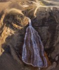 Rápida corriente estrecha que fluye a lo largo del terreno rocoso áspero y que cae de la pendiente de la montaña rígida en las tierras altas de Islandia - foto de stock