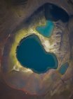 Прекрасный пейзаж кристально чистого озера на вулканском кратере в окружении грубой горной цепи, покрытой сухой растительностью в ясный день — стоковое фото