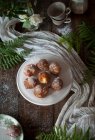 From above homemade custard cream fritters covered with sugar on rustic wooden table with table cloth and leafs decoration — Stock Photo