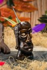 Brauner skulpturaler Tiki-Becher mit Alkoholgetränk, dekoriert mit Stroh und Eis auf dem Tisch — Stockfoto