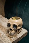 Керамічний полінезійський чашковий череп у формі тікі з соломою, розміщеною на дерев'яному столі на розмитому фоні — стокове фото