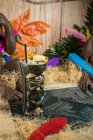 Von oben ein großer skulpturaler Tiki-Becher gefüllt mit Schnaps, der mit Stroh und Früchten auf einem grünen Teppich gegen trockenes Gras verziert ist — Stockfoto