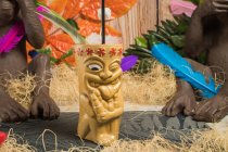 Polynesische Tiki-Tasse mit kaltem Alkohol, dekoriert mit Stroh und grünen Blättern gegen bunte Blätter und trockenes Gras — Stockfoto