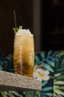Tiki-Tasse mit kaltem Alkohol-Getränk mit Stroh serviert mit Eis und dekoriert mit frischen Kräutern auf verschwommenem Hintergrund platziert — Stockfoto