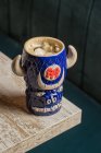 De cima de touro em forma de caneca tiki de bebida alcoólica com espuma colocada contra mesa de madeira no fundo borrado — Fotografia de Stock