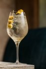 Хрустальное вино с коктейлем Мартини подается с лимонной цедрой и оливковым краем деревянного стола — стоковое фото