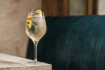 Crystal wineglass with Martini cocktail served with lemon zest and olives edge of wooden table — Stock Photo