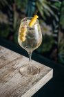 From above of crystal wineglass with Martini cocktail served with lemon zest and olives edge of wooden table — Stock Photo
