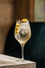 Verre à vin en cristal avec cocktail Martini servi avec zeste de citron et olives bord de la table en bois — Photo de stock