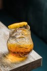 De cima da caneca de vidro tiki com bebida colocada na borda da mesa de madeira no quarto no fundo borrado — Fotografia de Stock