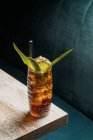 Сверху стеклянная кружка из тики, наполненная алкогольным напитком с соломой, украшенной фруктами, помещенными на краю деревянного стола дивана — стоковое фото