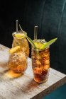 Dall'alto di occhiali tiki tazza piena di bevanda alcolica con paglia decorata con frutta posta sul bordo del divano da tavolo in legno — Foto stock